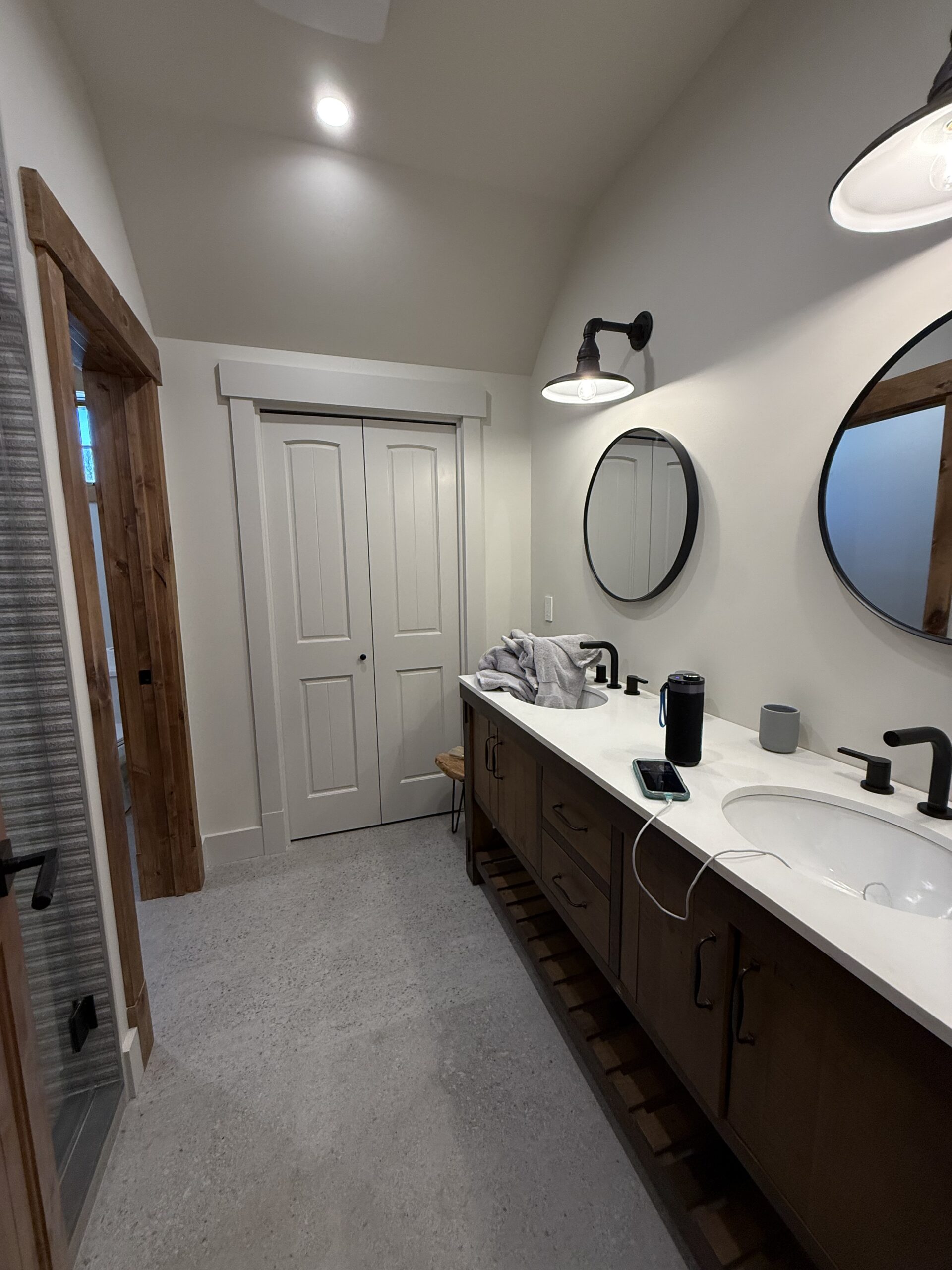 Bright primary bathroom with double vanity, black fixtures, and vaulted ceiling, finished by L&J Painting Group