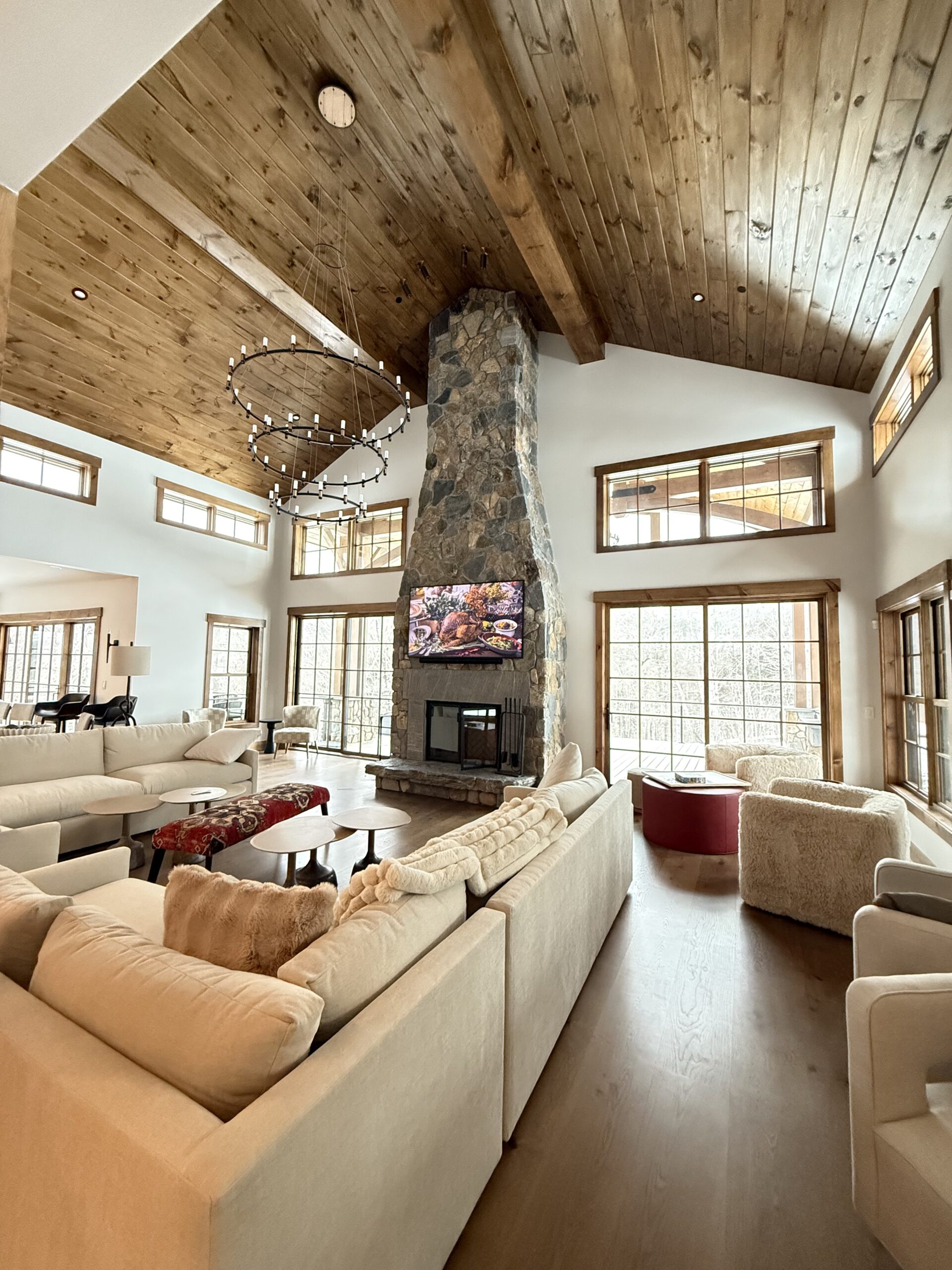 Vaulted great room with stone fireplace, wood-plank ceiling, and statement chandelier, finished by L&J Painting Group