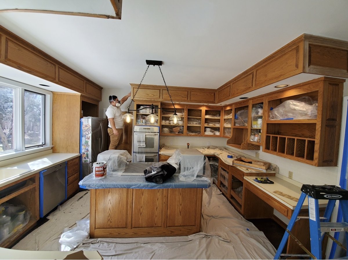 L&J Painting Group crew member spray-finishing kitchen cabinets