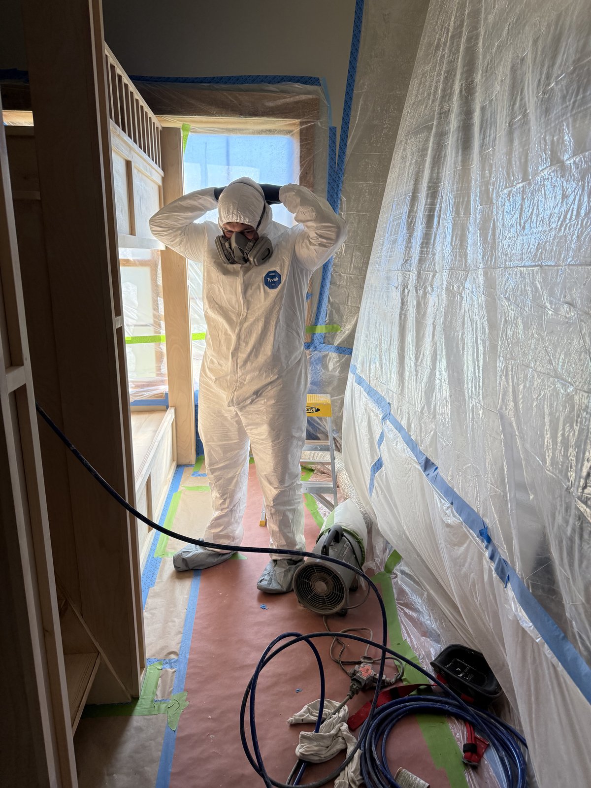 L&J Painting Group crew member in protective spray equipment during a fine finish spray painting project