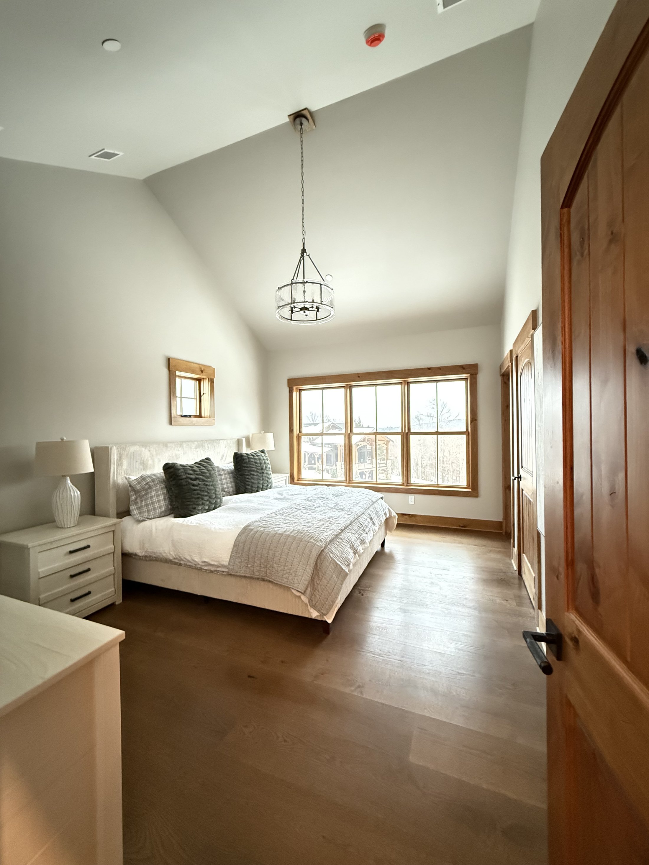 Bright primary bedroom with vaulted wood beam ceiling and natural light