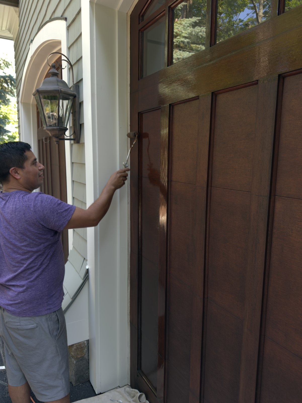 L&J Painting Group crew member staining an exterior door