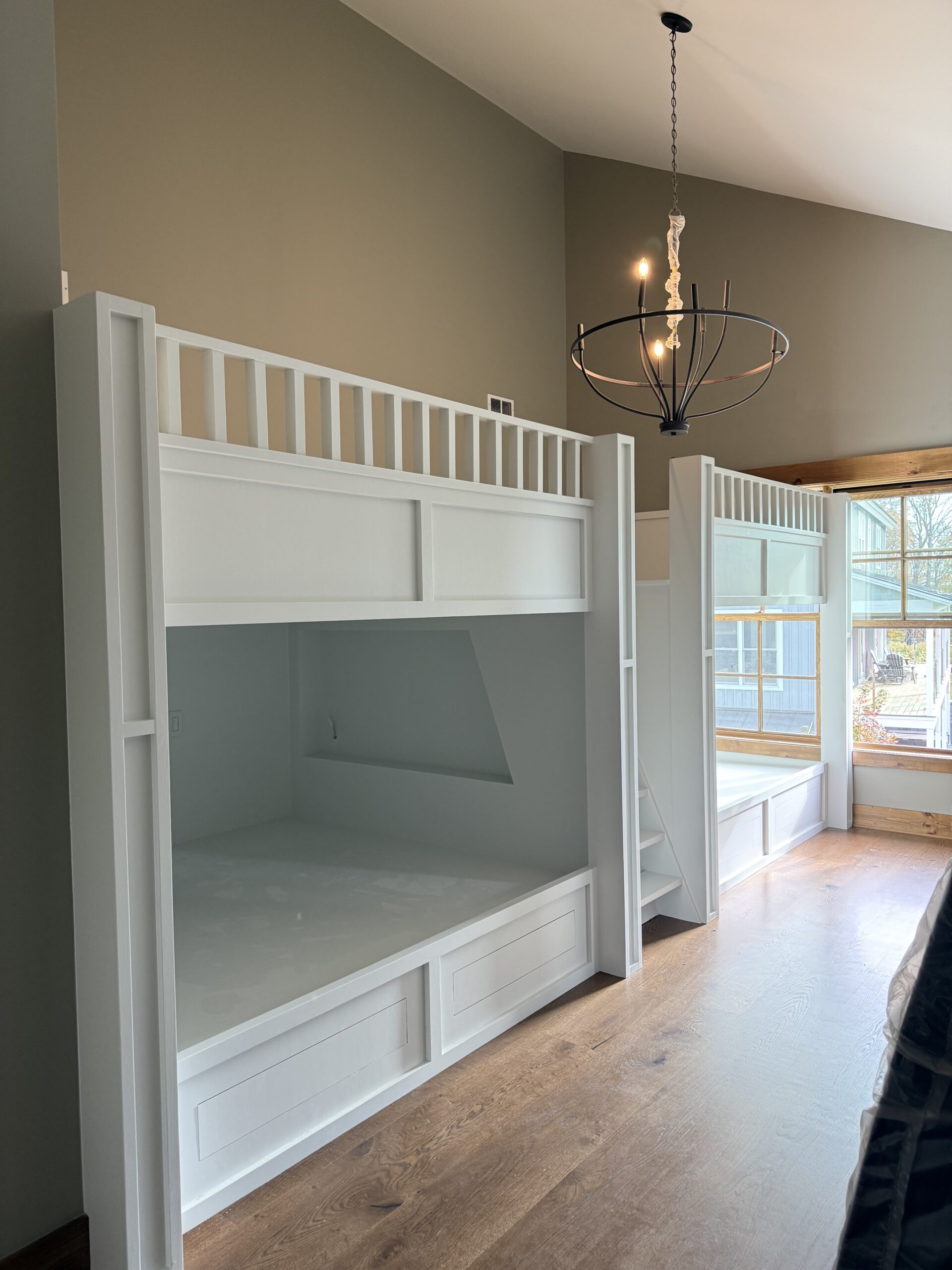 Custom built-in bunk room with vaulted ceiling and statement chandelier, finished by L&J Painting Group