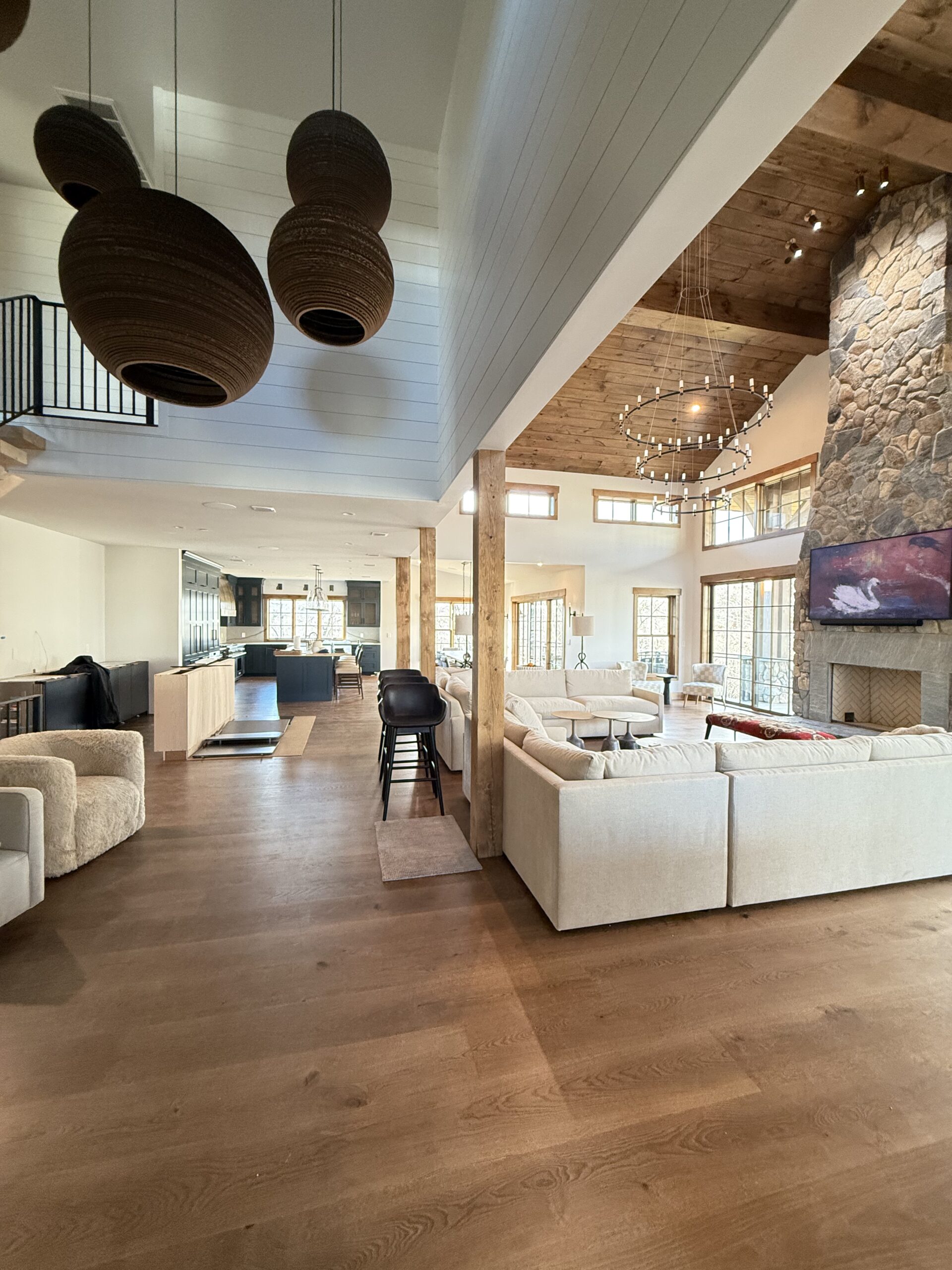 Bright vaulted great room with stone fireplace, shiplap ceiling, and woven pendant lighting