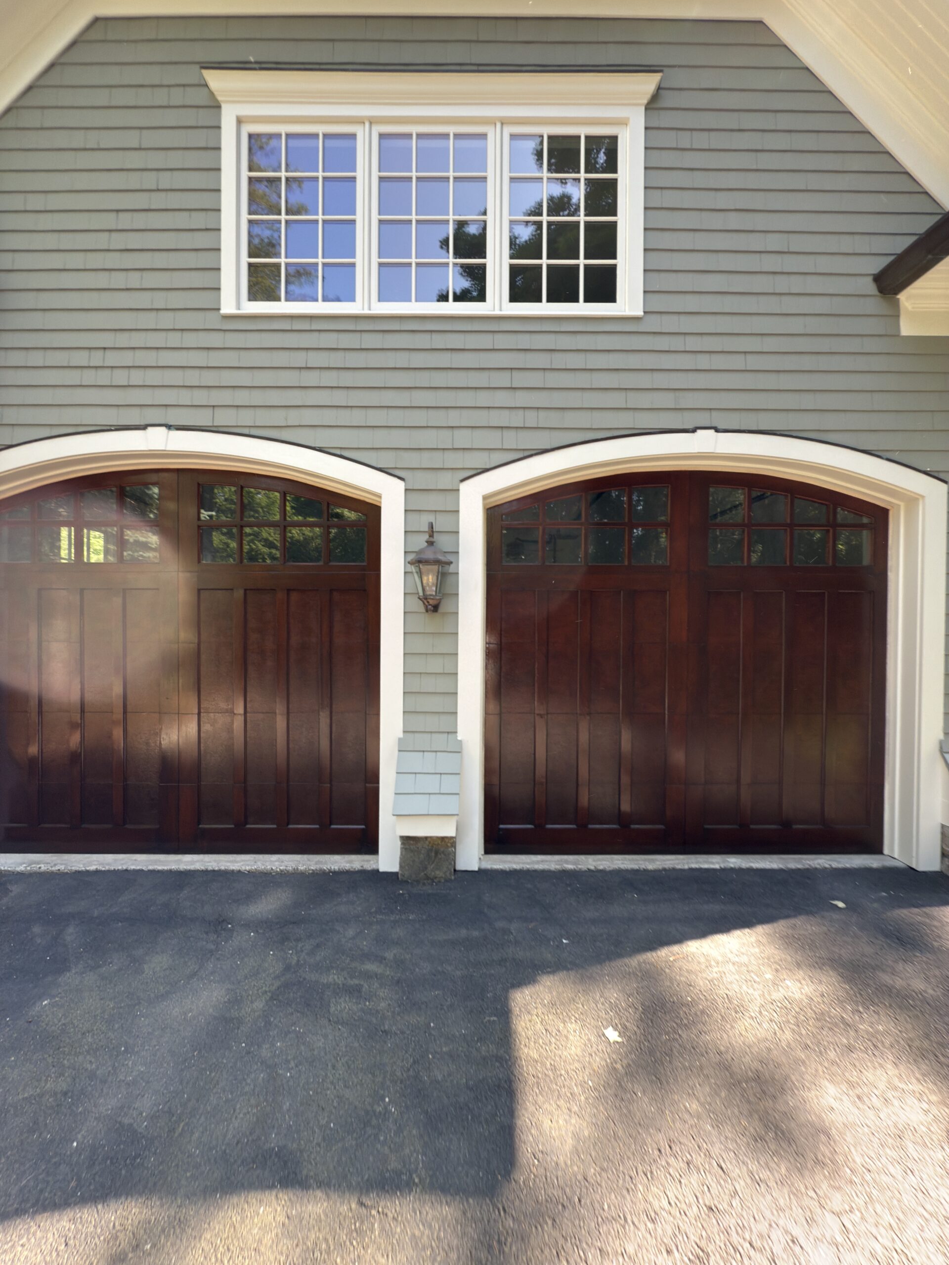 Finished stained wood carriage-style garage doors on a shingle-style home, by L&J Painting Group