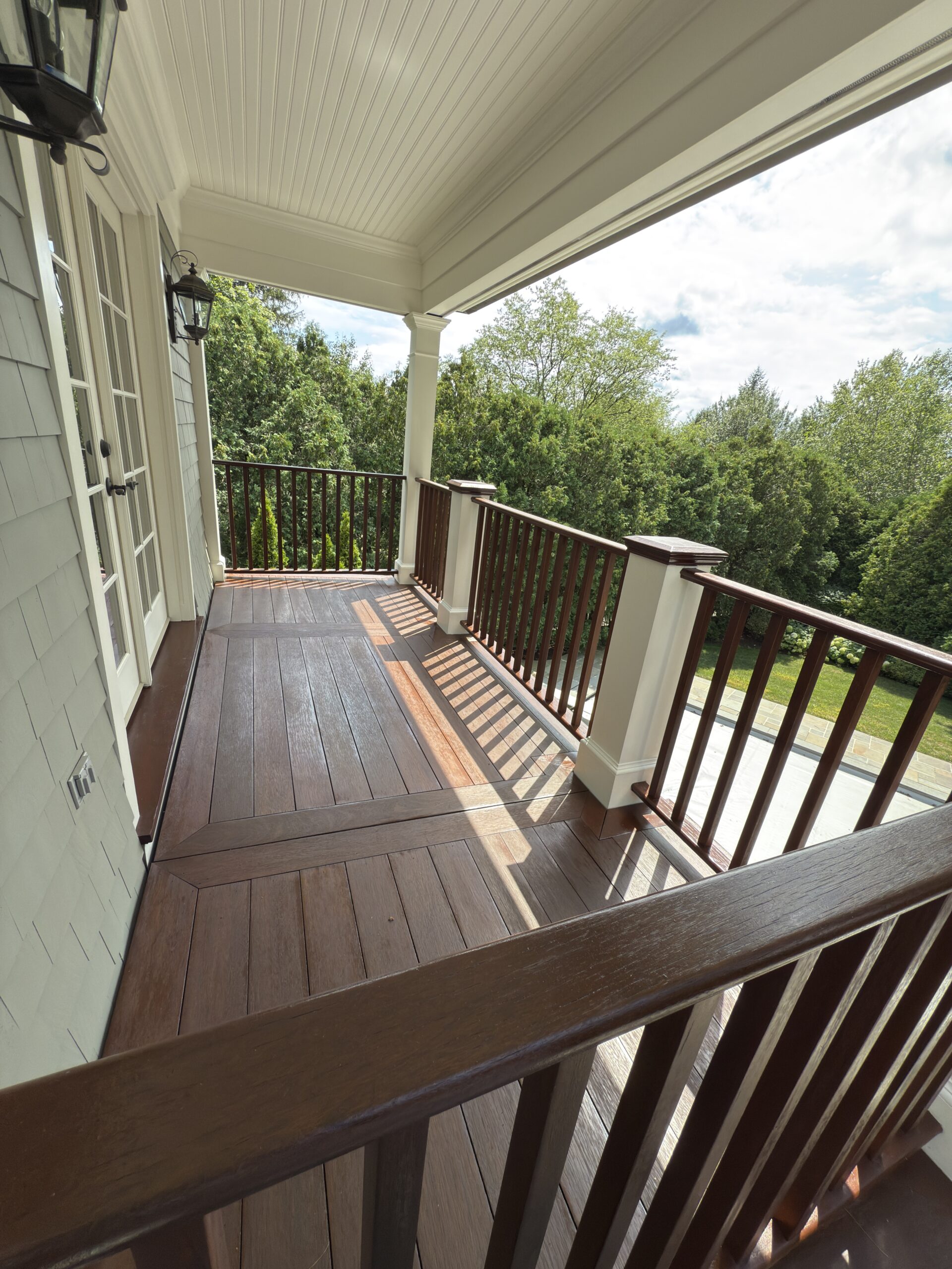 Finished stained porch decking with wood railings and tree views, by L&J Painting Group